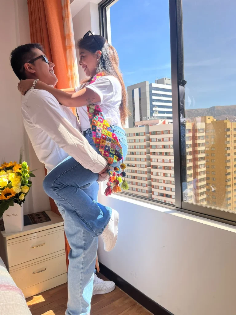 Paul y Carito en una habitación de hotel con vista a los edificios de La Paz