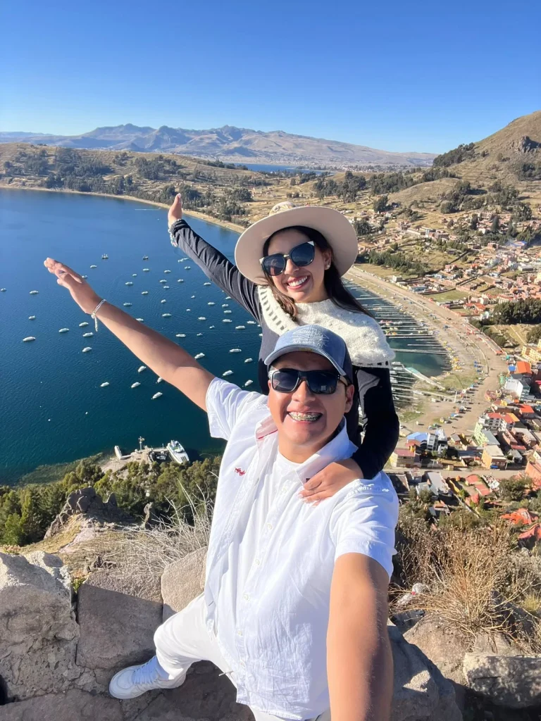Paul y Carito con los brazos abiertos en un mirador sobre la bahía de Copacabana y el lago Titicaca